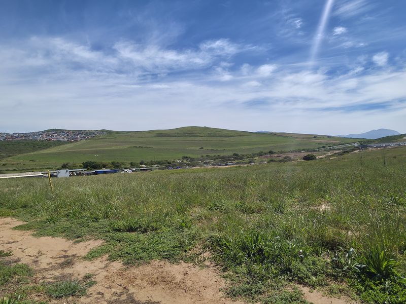 A wide-angle view of the vacant residential land, showcasing the surrounding landscape and distant neighborhood.