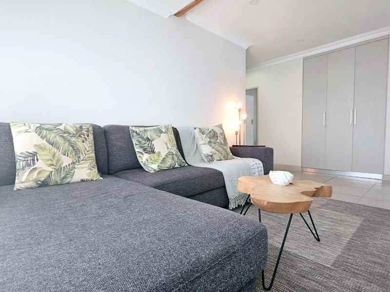 A well-maintained living area featuring neutral tiled flooring, built-in storage cupboards, and clean white walls with decorative ceiling cornicing.
