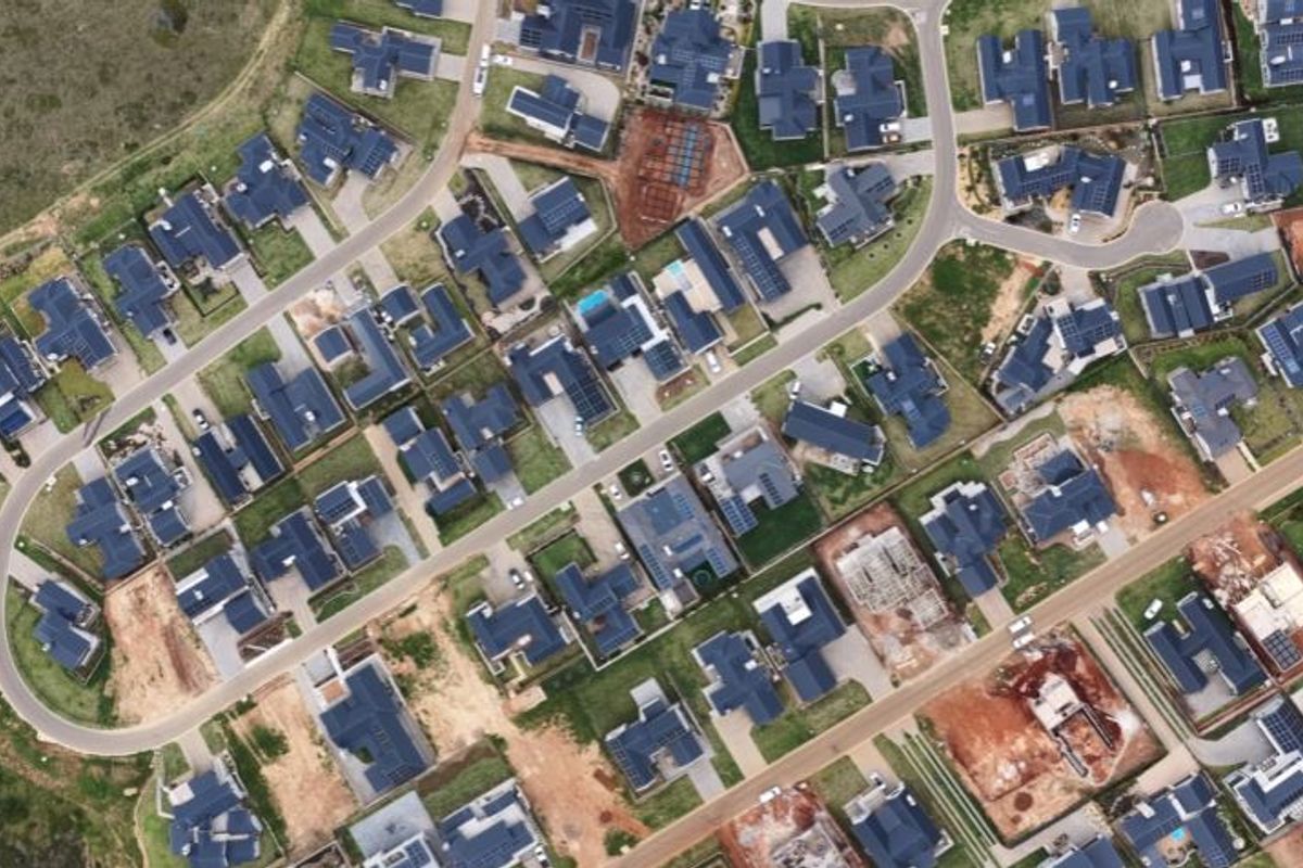 An aerial view of a residential estate showing the layout of houses, streets, and vacant plots within the neighborhood.