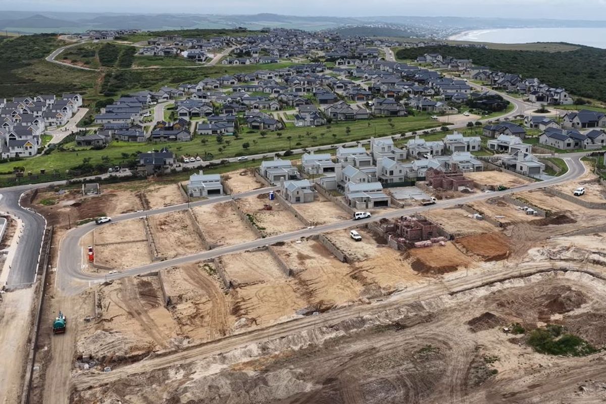 Aerial view of a residential development site showing cleared plots, paved roads, and ongoing construction within a coastal estate.
