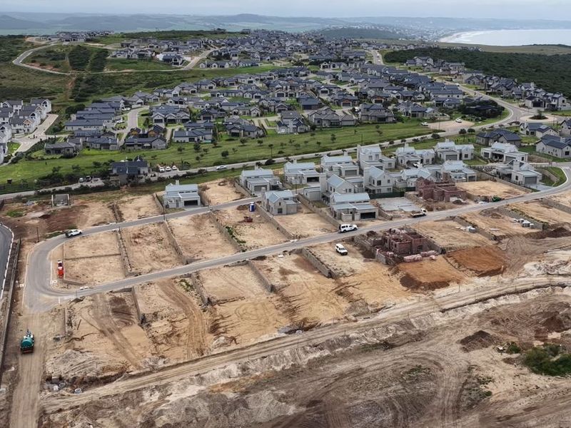 Aerial view of a residential development site showing cleared plots, paved roads, and ongoing construction within a coastal estate.