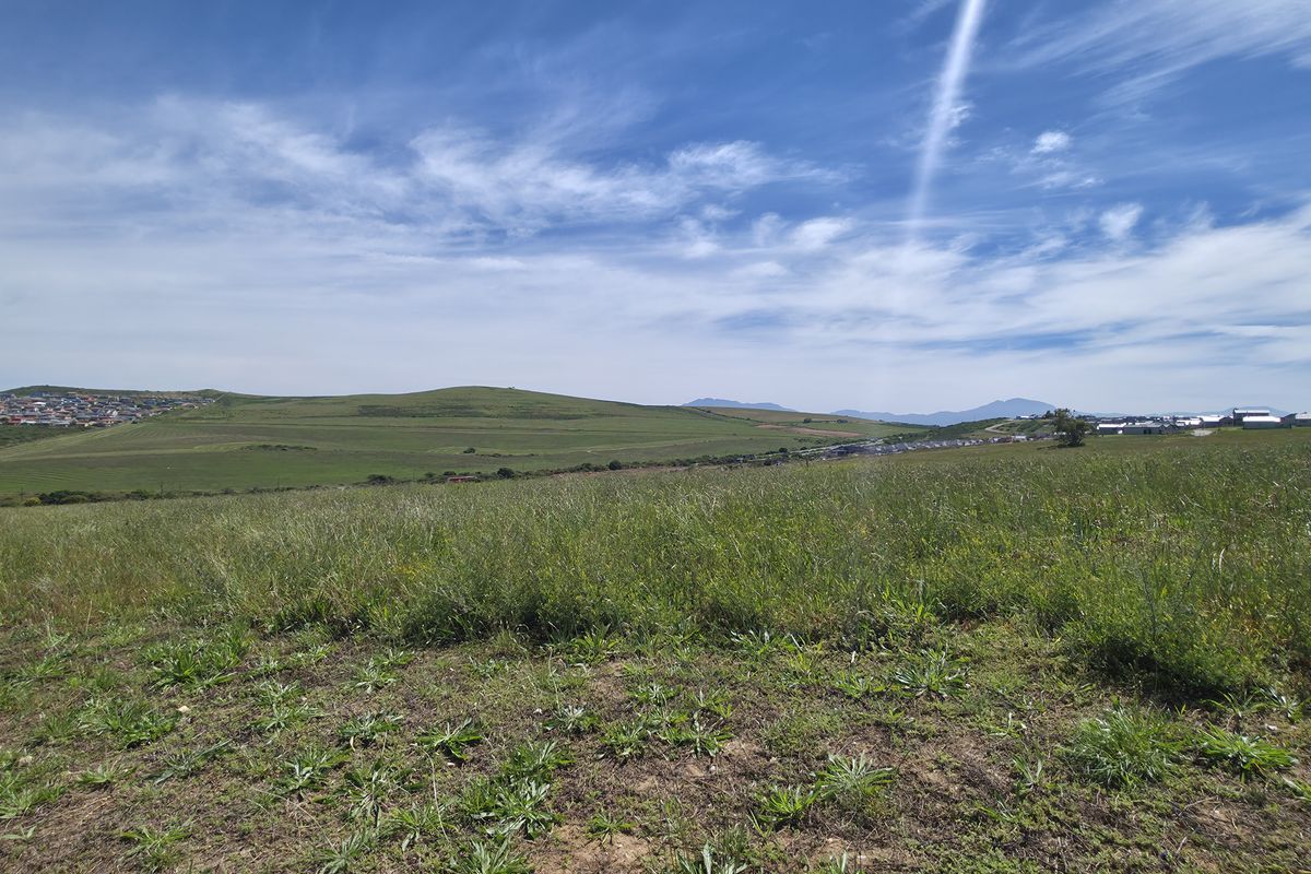 A wide-angle view of the vacant residential land, showcasing the surrounding landscape and distant hillside terrain.
