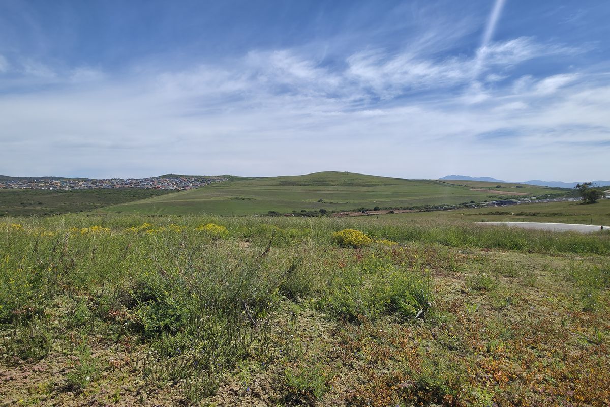 A wide-angle view of the vacant residential land, showcasing the surrounding landscape, rolling hills, and distant neighborhood development.