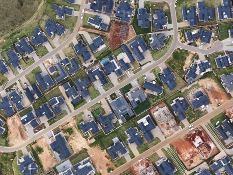 An aerial view of a residential estate showing the layout of houses, streets, and vacant plots within the neighborhood.