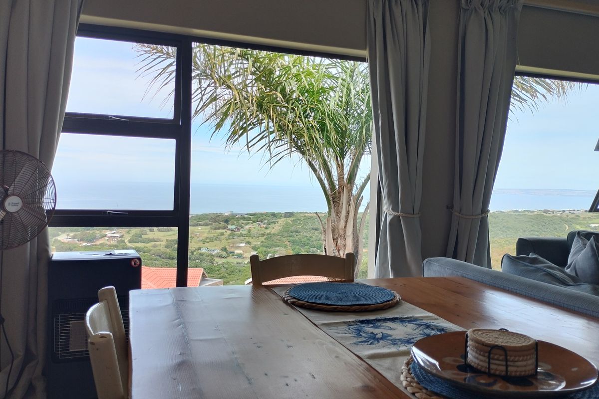A living area featuring large windows that provide expansive coastal and landscape views, allowing for significant natural light.