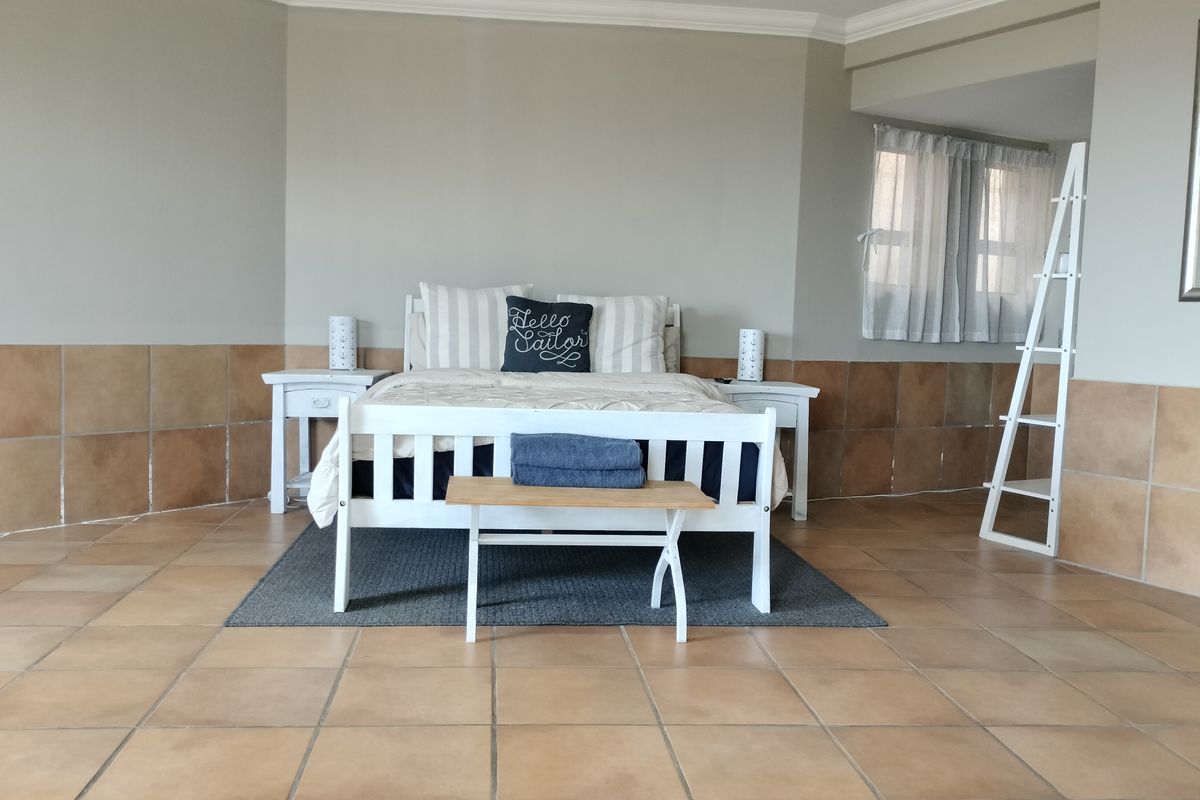 Spacious bedroom featuring neutral wall paint, ceramic floor tiles, and decorative half-wall tiling throughout the room.