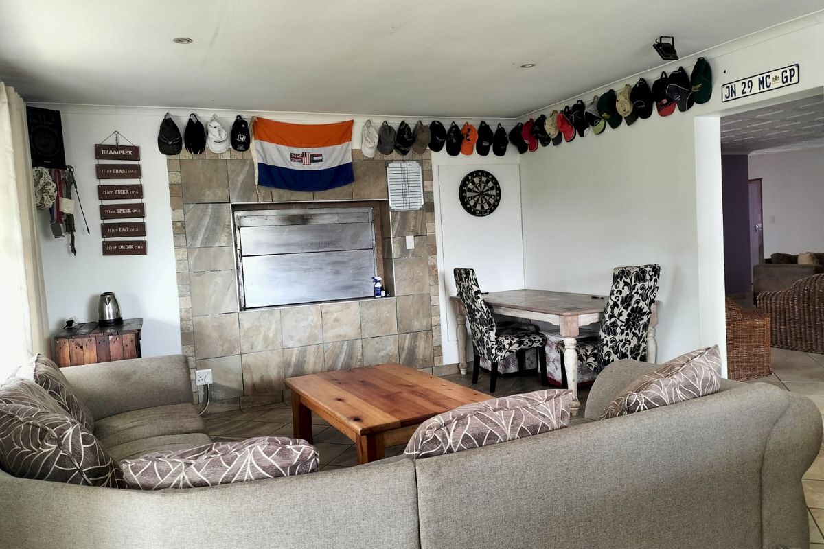 A living area featuring a built-in braai with tiled surround, recessed lighting, and tiled flooring, offering a functional space for indoor entertaining.