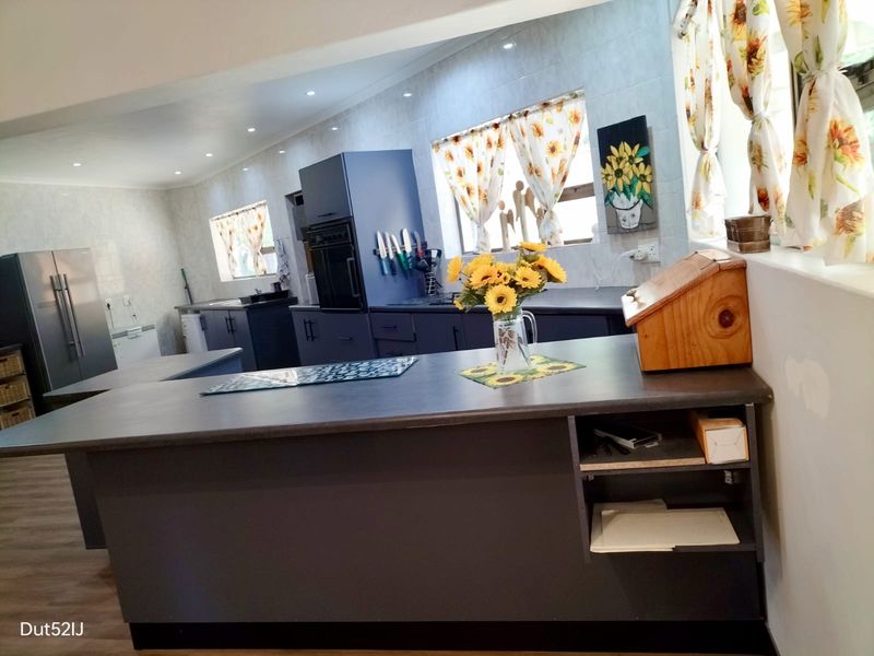 Modern kitchen featuring dark cabinetry, a central island, built-in oven, and recessed lighting, offering a functional workspace with ample storage.