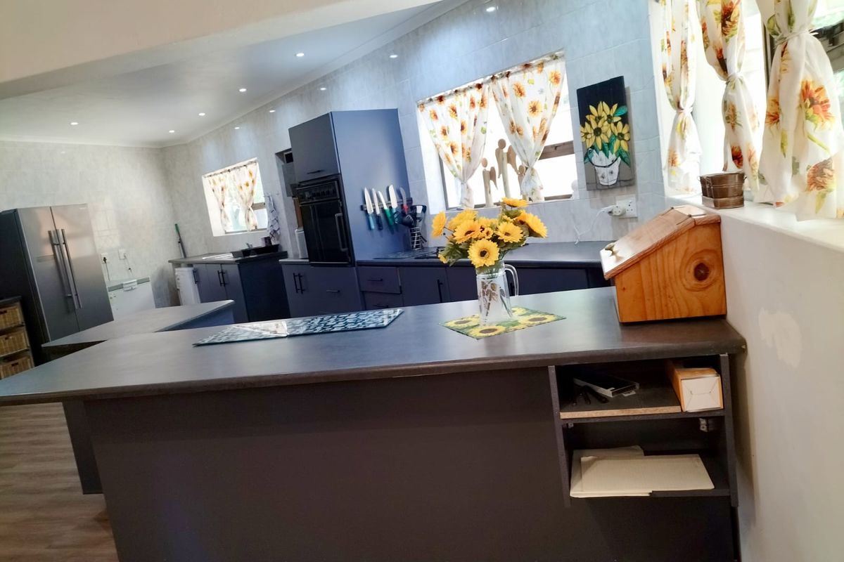 Modern kitchen featuring dark cabinetry, a central island, built-in oven, and recessed lighting, offering a functional workspace with ample storage.