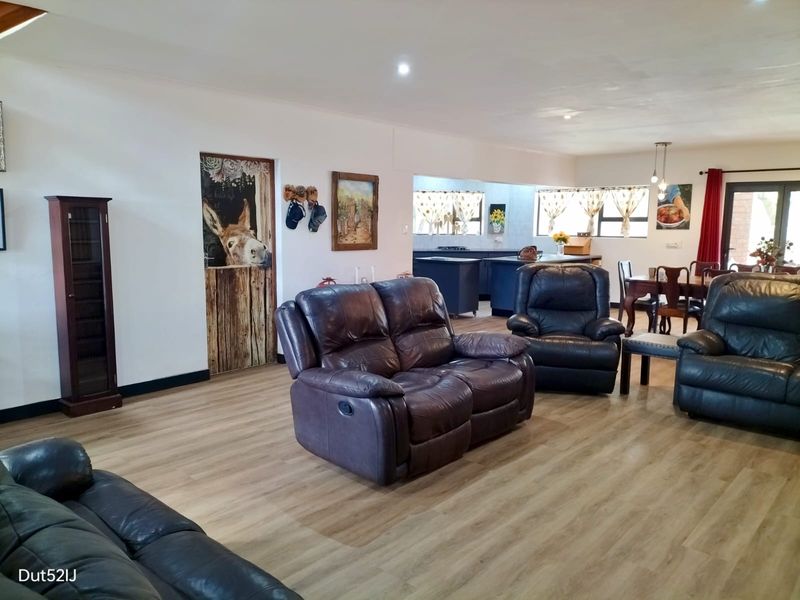 Spacious open-plan living area featuring modern laminate flooring, recessed lighting, and a seamless flow into the adjacent kitchen space.
