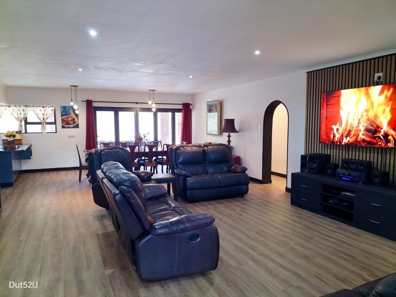Spacious open-plan living and dining area featuring modern laminate flooring, a decorative slatted timber feature wall, and direct access to the outdoor space.