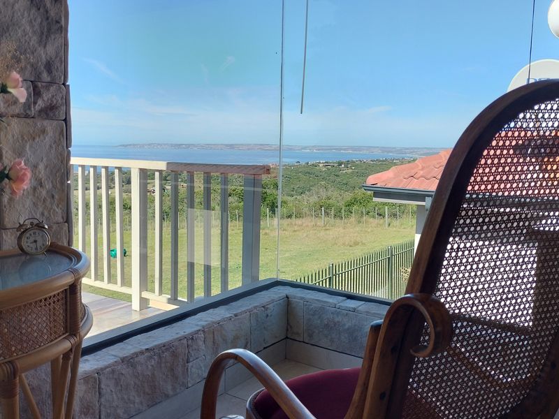 Enclosed balcony featuring stone cladding and expansive views of the surrounding landscape and coastline.