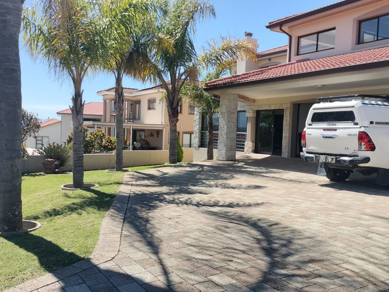 A well-maintained front exterior featuring a paved driveway, stone-clad pillars, and a landscaped garden area leading to the main entrance.