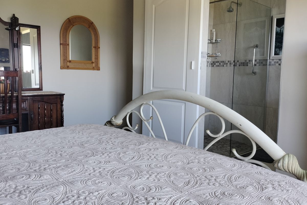 Bedroom featuring an en-suite bathroom with a glass-enclosed shower, tiled finishes, and integrated grab rail.