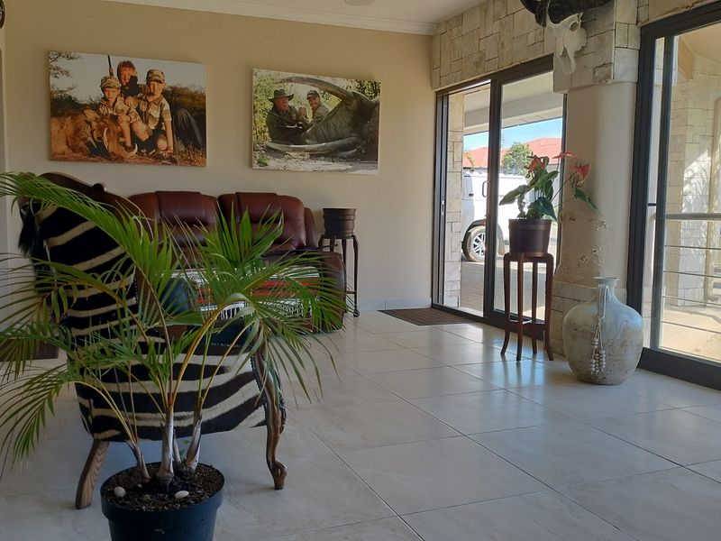 A bright living area featuring large sliding glass doors, neutral tiled flooring, and a decorative stone-clad feature wall.