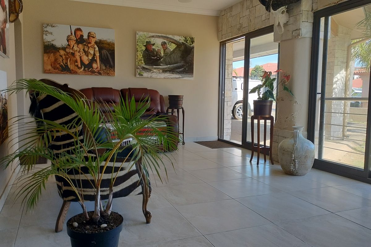 A bright living area featuring large sliding glass doors, neutral tiled flooring, and a decorative stone-clad feature wall.