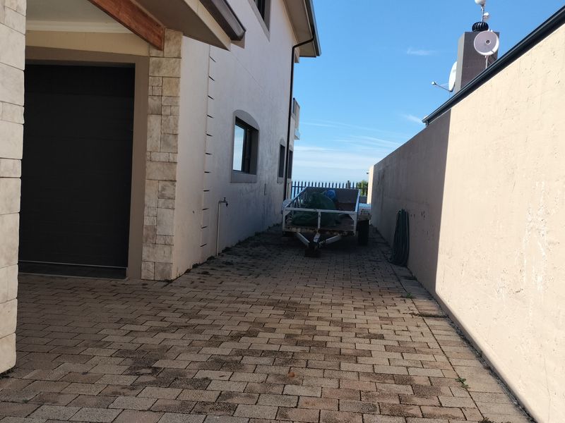 Side access area featuring paved driveway, external water tap, and boundary wall, leading towards the rear of the property.