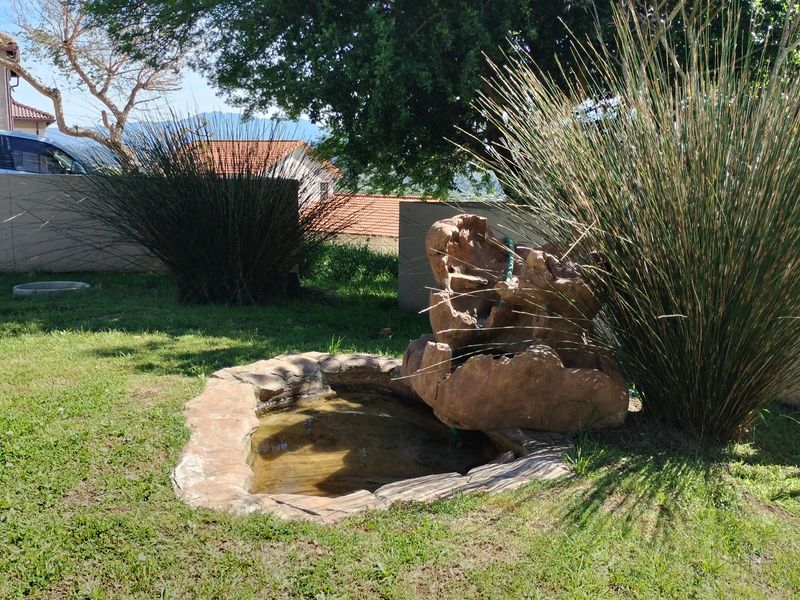 A landscaped garden area featuring a natural stone water feature and established boundary walling.