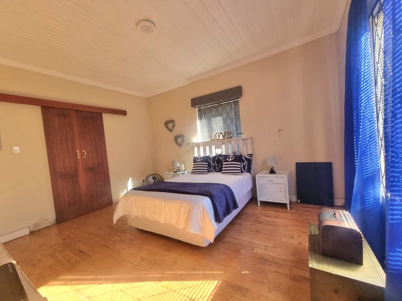 A bedroom featuring timber flooring, a tongue and groove ceiling, and a wooden sliding barn door, with some visible wear on the walls.