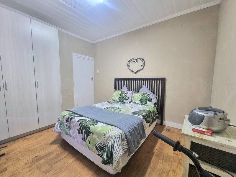 A functional bedroom featuring built-in cupboards, laminated flooring, and a classic tongue and groove ceiling finish.