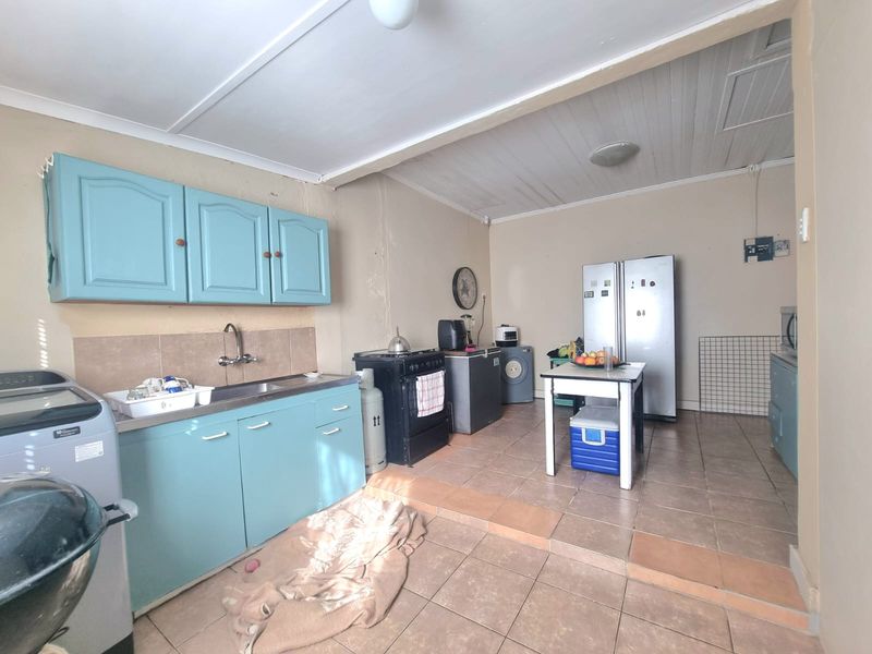 A functional kitchen featuring blue cabinetry, tiled flooring, and a gas stove, offering potential for modernization and aesthetic updates.