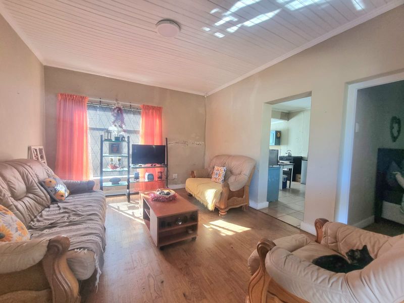 A living room featuring timber-look flooring and a tongue and groove ceiling, with visible wall plaster damage requiring repair.
