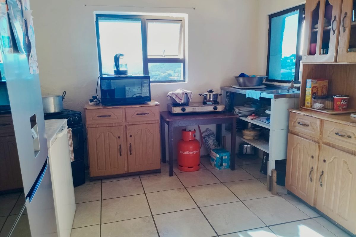 A functional kitchen area featuring tiled flooring, wooden cabinetry, and a window providing natural light.