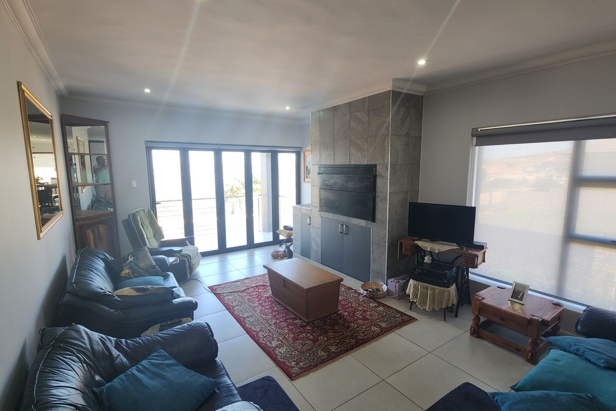 Spacious living room featuring large format floor tiles, a stone-clad built-in fireplace, and expansive sliding glass doors leading to an outdoor area.