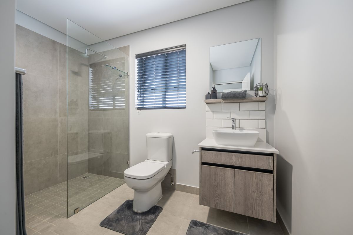 Modern bathroom featuring a frameless glass walk-in shower, wall-mounted vanity with vessel sink, and subway tile backsplash.