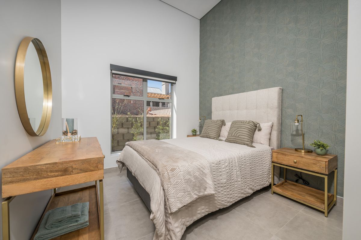 A modern, well-lit bedroom featuring neutral floor tiles, a textured feature wall, and a large window providing natural light.