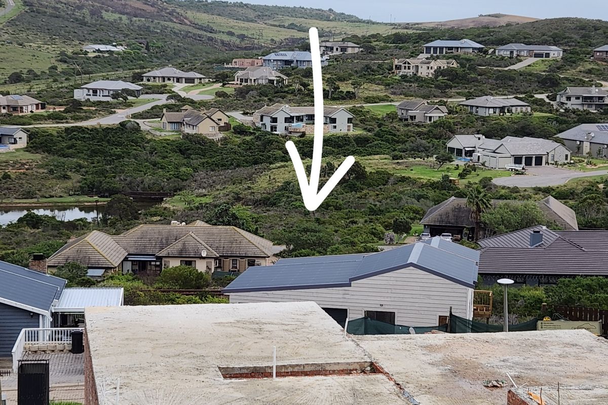 An elevated aerial view of a residential neighborhood showing surrounding properties and the vacant land plot indicated by the arrow.