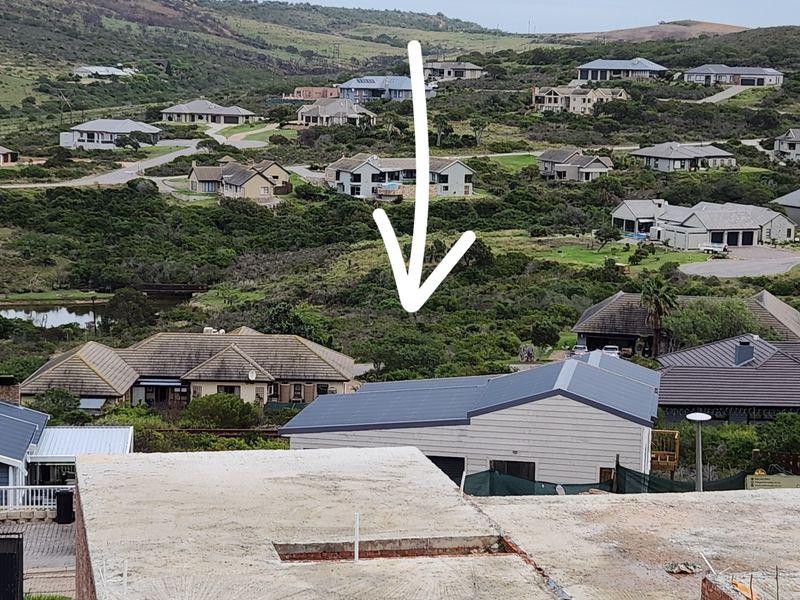 An elevated aerial view of a residential neighborhood showing surrounding properties and the vacant land plot indicated by the arrow.