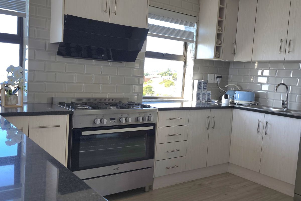 Modern kitchen featuring light wood cabinetry, subway tile backsplash, dark stone countertops, a gas stove with extractor fan, and integrated dishwasher space.