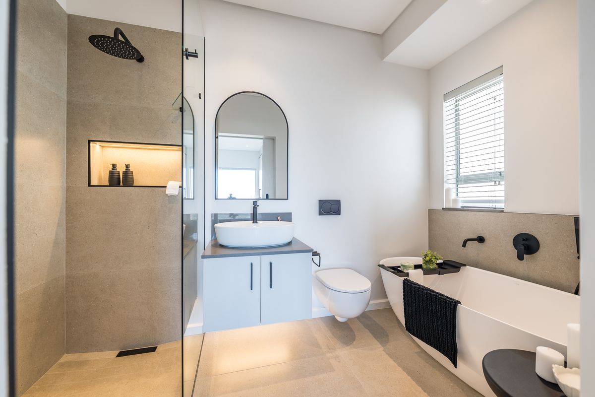 Modern bathroom featuring a walk-in shower with rainfall head, wall-mounted vanity with vessel sink, and a freestanding bathtub with matte black fixtures.