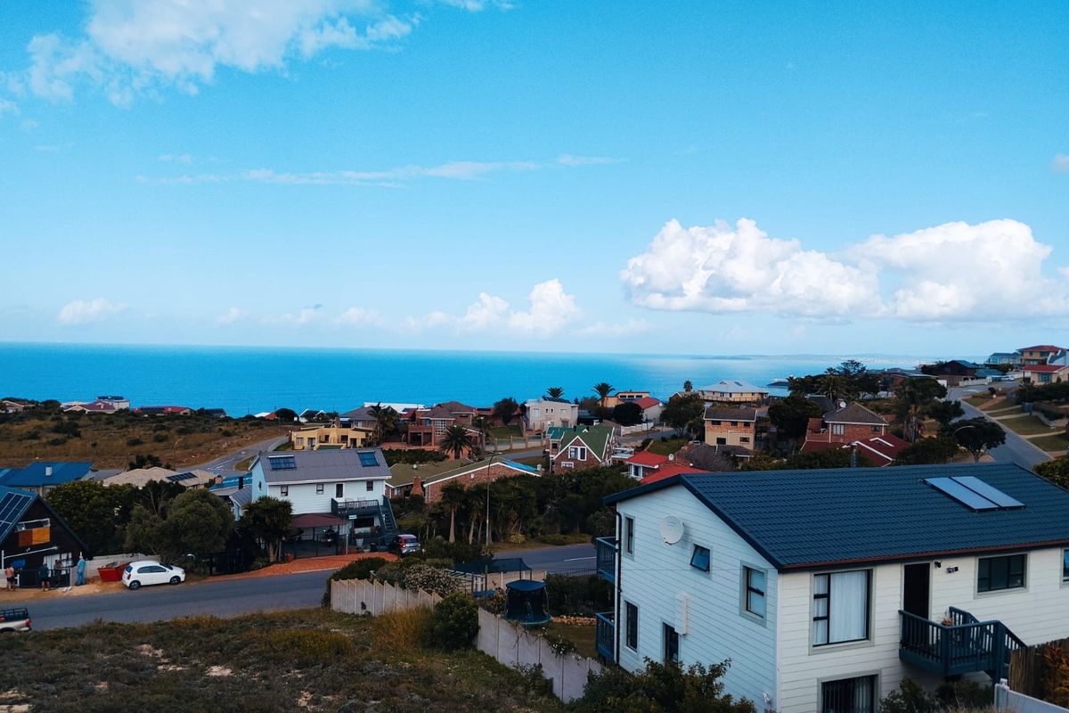Elevated aerial view overlooking a coastal residential neighborhood with ocean vistas in the background.