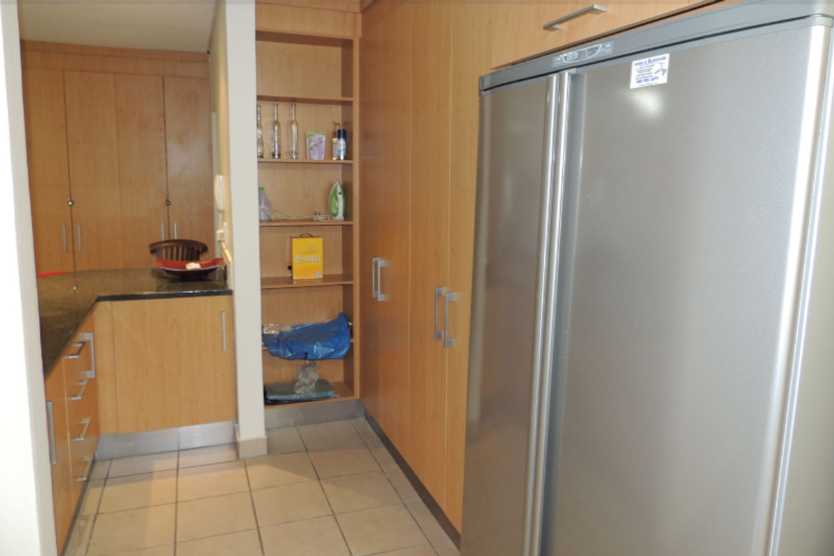 A functional kitchen area featuring light wood cabinetry, granite countertops, tiled flooring, and integrated storage shelving.