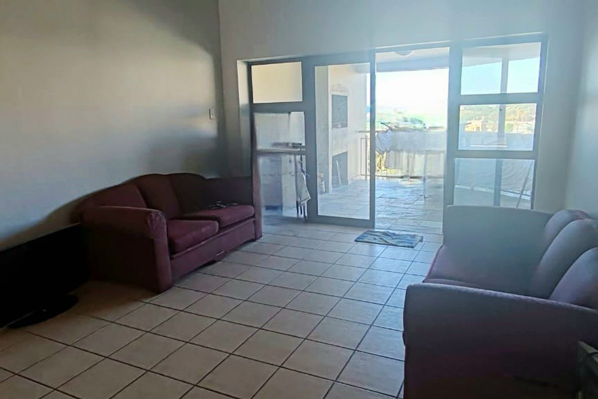 A living room featuring tiled flooring and large glass sliding doors that provide access to an outdoor patio area.