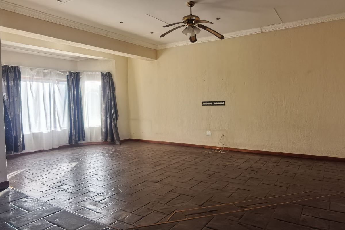 Spacious living area featuring tiled flooring, a ceiling fan, and a decorative partition wall, offering a versatile layout for comfortable family living.