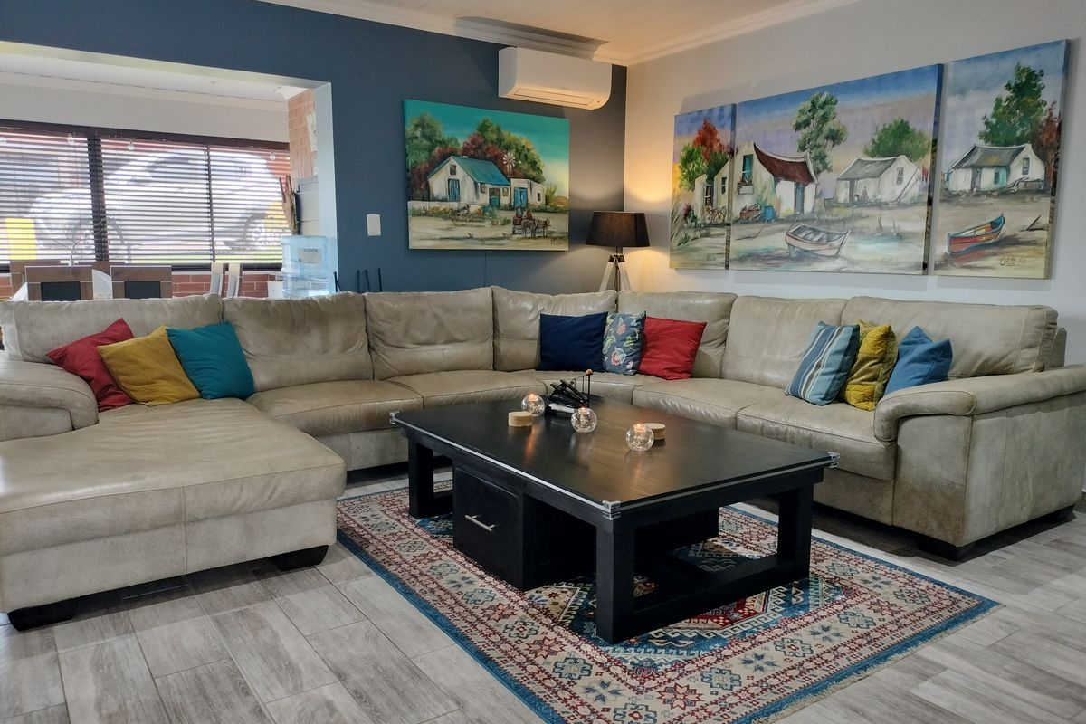 A comfortable living room featuring modern tiled flooring, a wall-mounted air conditioning unit, and a neutral color palette with a bold accent wall.