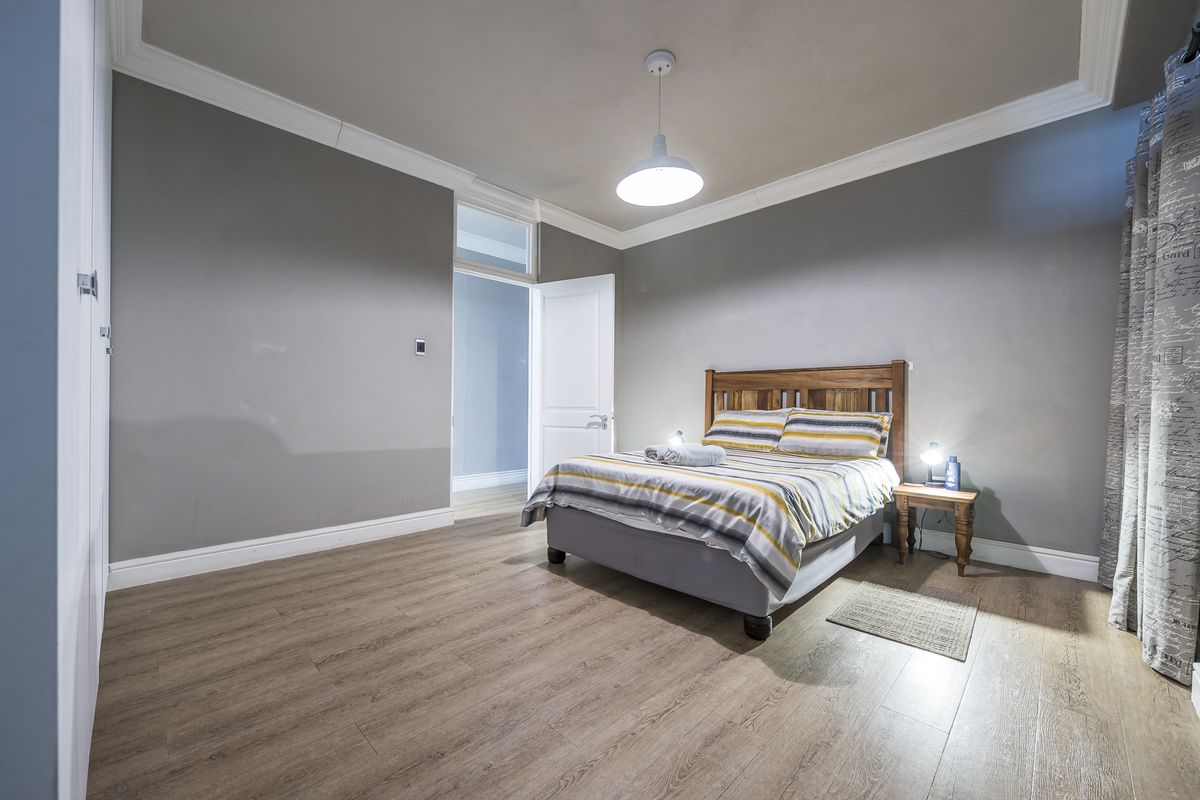 A spacious bedroom featuring laminate flooring, crown molding, and a built-in wardrobe, offering a neutral and well-maintained living space.