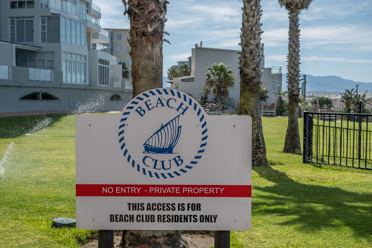 A view of the landscaped communal garden area and lawn within the private Beach Club residential complex.
