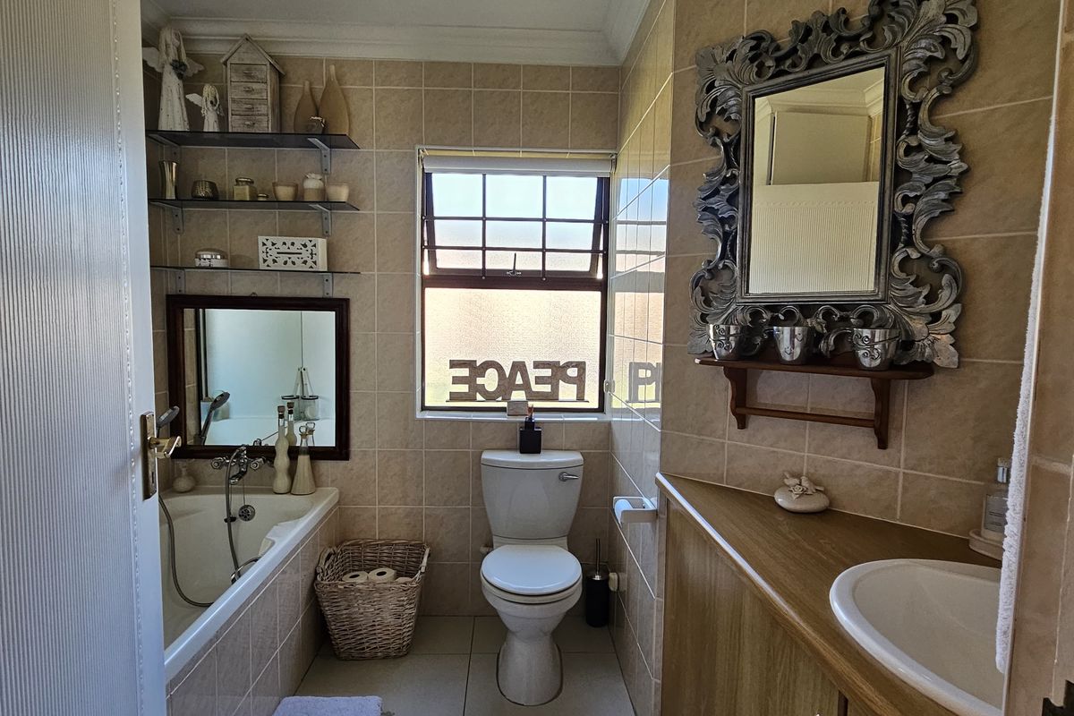 A functional bathroom featuring a built-in vanity with basin, a bathtub, and neutral wall and floor tiling.