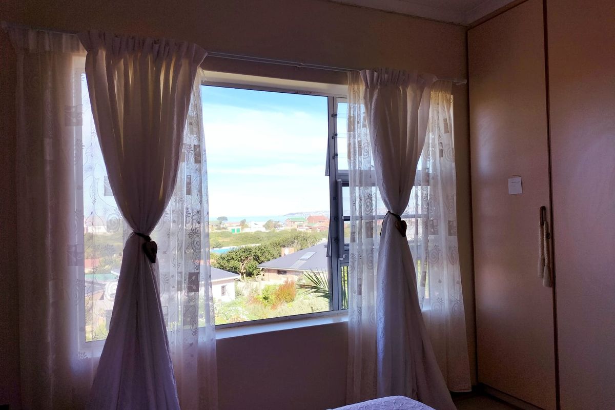 A bedroom featuring built-in cupboards and a large window offering scenic neighborhood views.