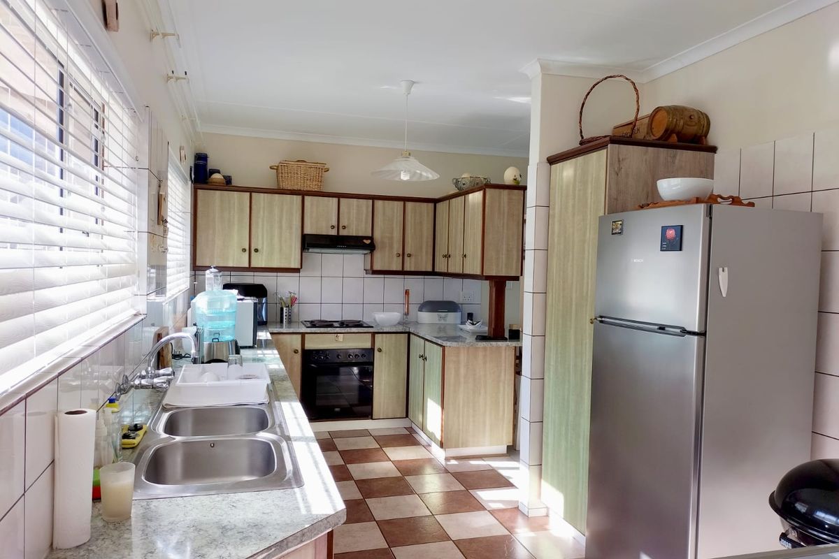 Functional kitchen featuring laminate countertops, double basin sink, built-in oven, hob, extractor fan, and ample cabinetry with tiled splashbacks.