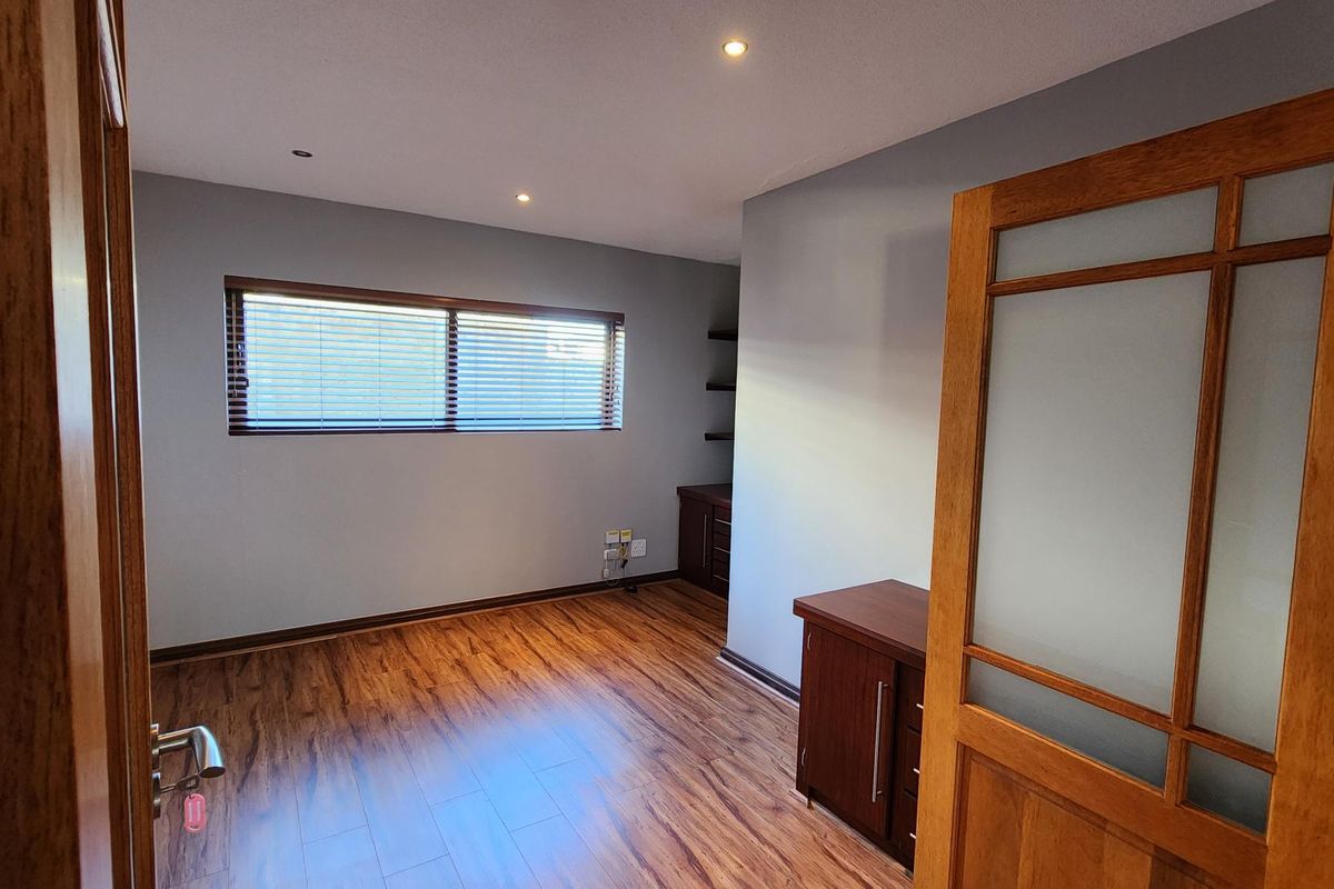 A well-maintained bedroom featuring wood-look laminate flooring, recessed ceiling lighting, and built-in wooden cabinetry with shelving.