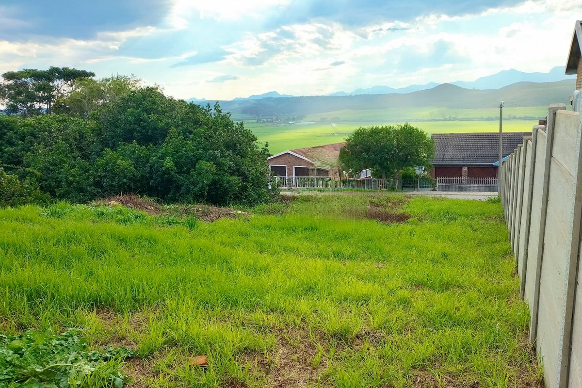 A view of a vacant residential plot featuring a precast concrete boundary wall and surrounding landscape views.