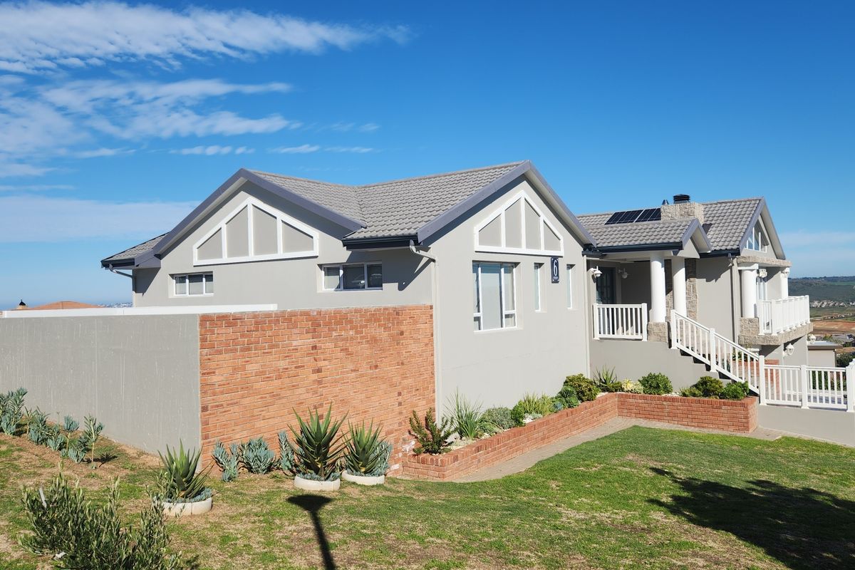 Exterior view of a well-maintained house featuring a tiled roof, brick retaining walls, landscaped garden, and elevated balcony area.
