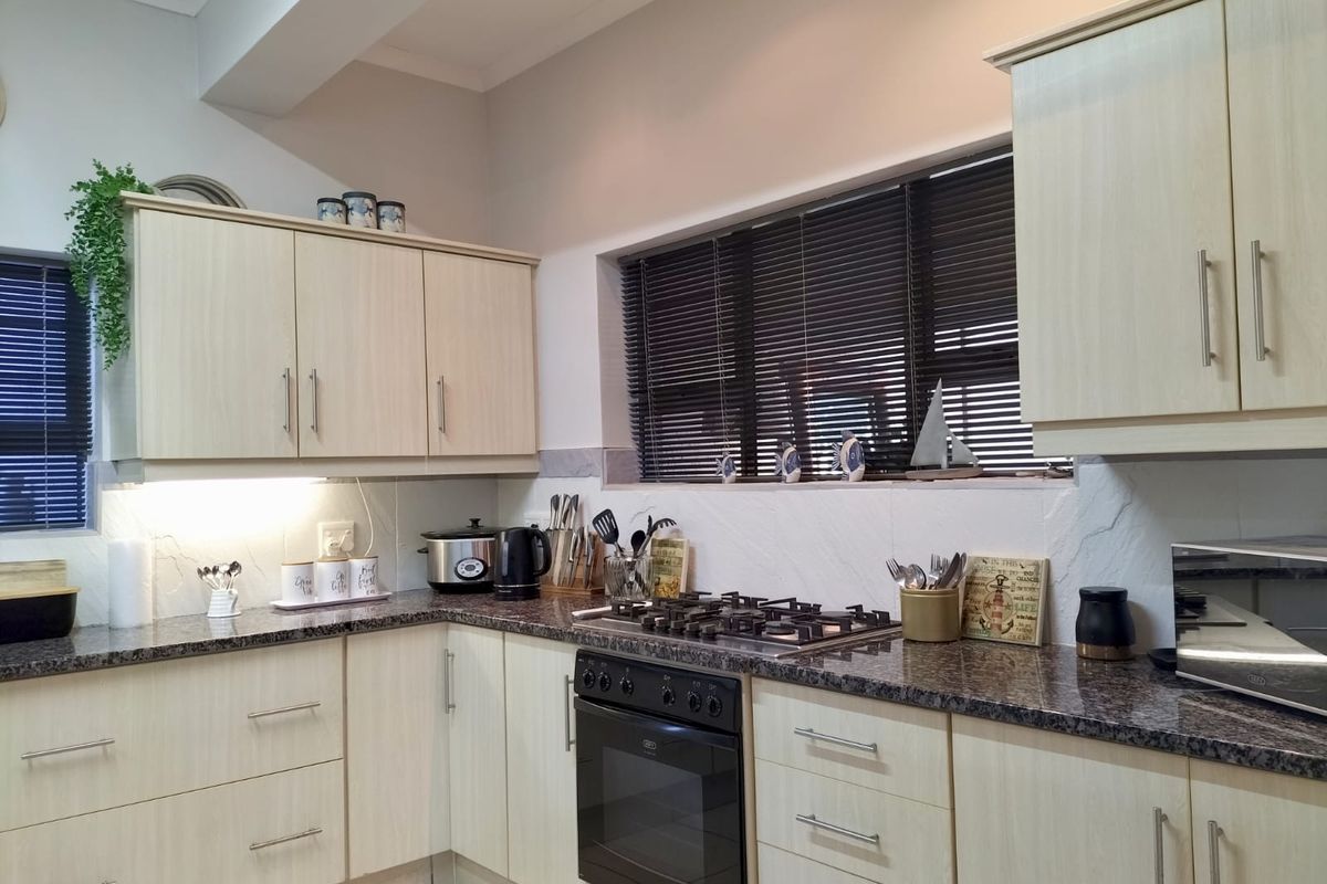 A well-maintained kitchen featuring light wood-grain cabinetry, granite countertops, a built-in oven, and a gas hob with an integrated backsplash.