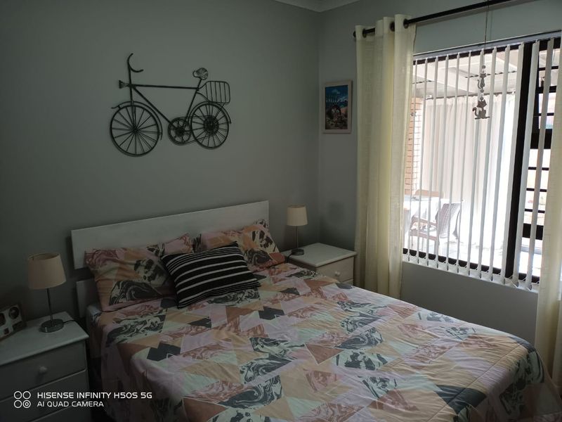 A well-maintained bedroom featuring neutral wall tones, vertical window blinds, and a curtain rod, providing a comfortable and functional sleeping space.