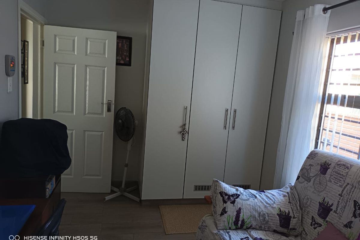 A bedroom featuring built-in cupboards and laminate flooring, providing functional storage and a neutral base for interior design.